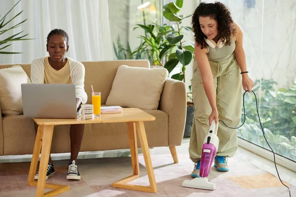 College Student Working Laptop Her Roommate Vacuum Cleaning Floor — Stock Photo, Image