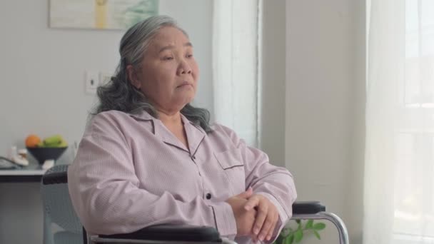 Tekerlekli Sandalyedeki Üzgün Yaşlı Asyalı Kadının Evine Bakan Orta Boy — Stok video