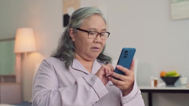 Średnie Ujęcie Skoncentrowanej Azjatki Okularach Piżamie Piszącej Sms Przez Telefon — Wideo stockowe