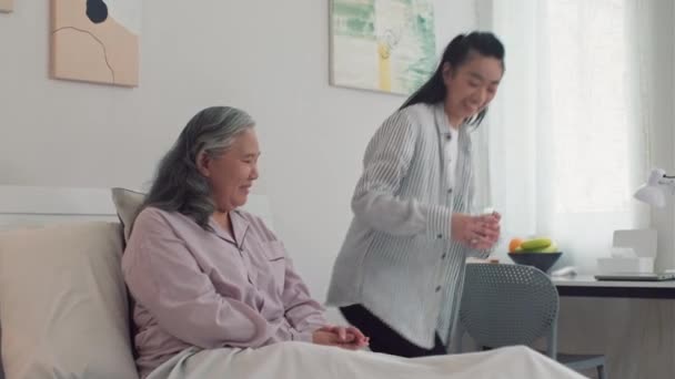在疗养院卧床休息时 中等剂量的熟女病人从她的小女儿手里接过一杯水 — 图库视频影像