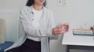 Asyalı kızın hasta annesine evini ziyaret ederken bir bardak su verdiği orta boy bir fotoğraf.