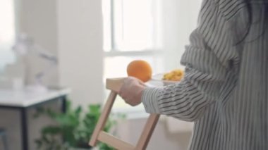 Bakımlı Asyalı kız hasta ana tepsisini portakal ve yatağın üzerine getiriyor.