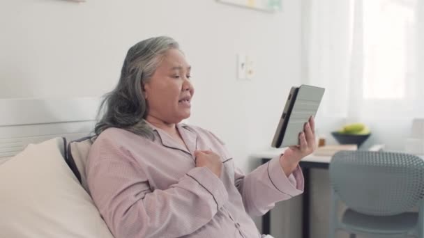 잠옷을 노인의 침대에서 디지털 태블릿에 통화에 그녀의 이야기 — 비디오