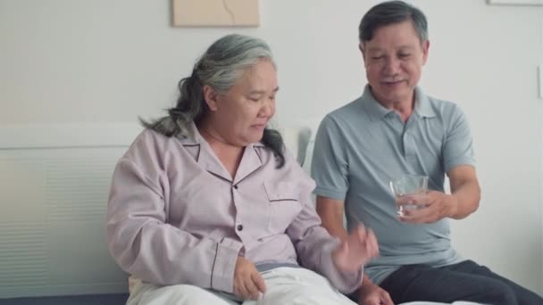 亚洲丈夫在家中卧床照顾生病的妻子 给她治病的药和水 — 图库视频影像