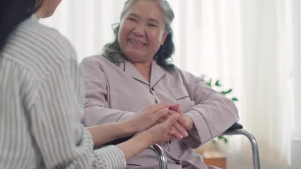 在疗养院与坐在轮椅上快乐的老年妇女交谈时 女性护理人员的肩膀上方的视角 — 图库视频影像