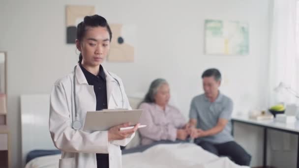 Portret Młodego Azjatyckiego Lekarza Białym Płaszczu Wypełniającego Kartę Medyczną Chorego — Wideo stockowe