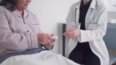 Terapistin, hasta yaşlı bayana hastanede bakıcılık yaparken ilaç ve su verirken çekilmiş görüntüsü.