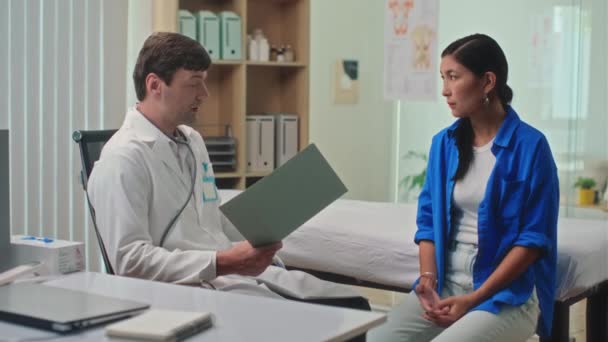 診療所訪問中に女性患者に診断を説明する医療従事者の中長撮影 — ストック動画