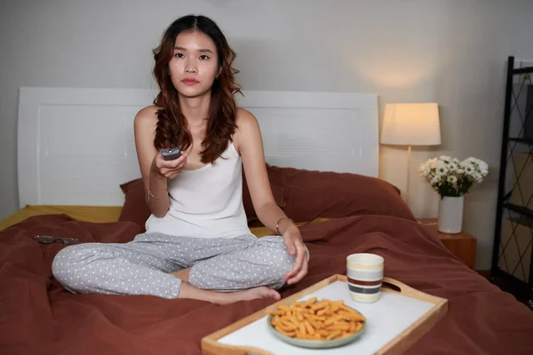 Girl spending time at home alone, eating snacks and watching tv