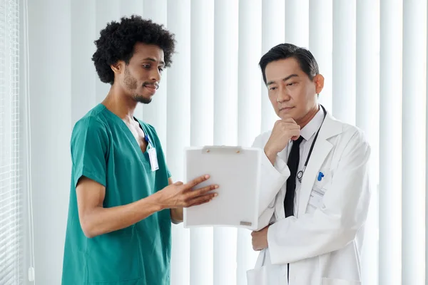 Nurse showing medical history of patient to doctor