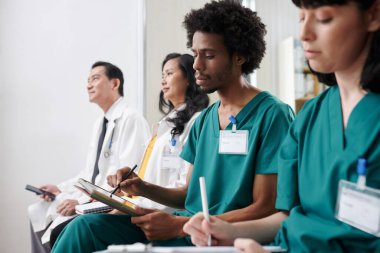 Hastane çalışanları toplantısına giderken tablet bilgisayara not alan ciddi bir tıp hemşiresi.