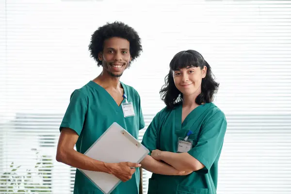 Portrait of medical nurses in green scrubs smiling at camera
