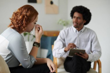 Genç bir kadın onunla konuşurken gözyaşlarını siliyor.