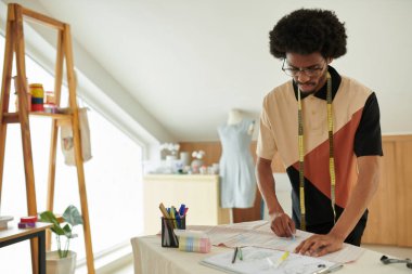 Moda tasarımcısı mavi tebeşirle kumaş üzerine çizim yapıyor