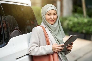 Tablet bilgisayarlı tesettürlü gülümseyen Müslüman iş kadını portresi