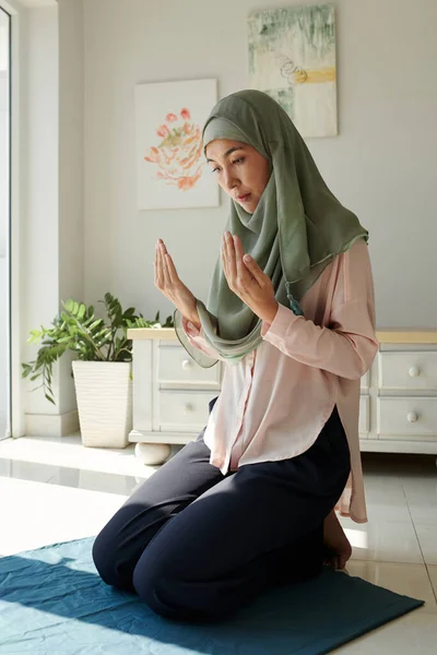 Muslim woman in hijab praying at home, faith and spirituality concept