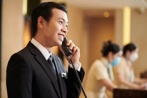 Vietnamese spa hotel manager talking on phone with guest ordering breakfast in room