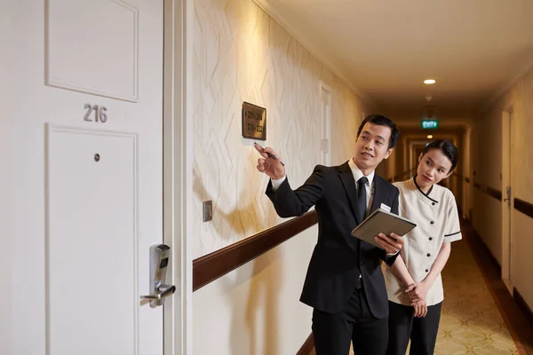 Hotel manager explaining maid which rooms need to be cleaned