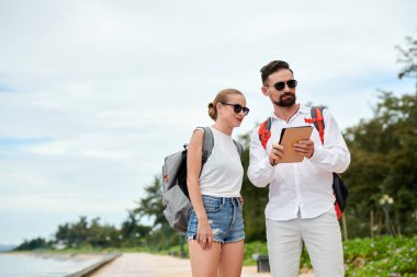 Gülümseyen turistler otel ararken tablet bilgisayarda uygulama kullanıyorlar