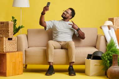 Gözlüklü mutlu adam selfie çekiyor ve barış jesti yapıyor.