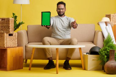 Yeşil ekranlı tablet bilgisayarı gösteren neşeli bir adam başparmak işareti yapıyor