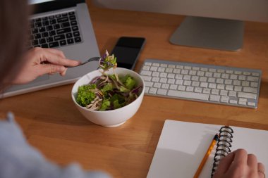 Salata yiyen ve planlamacıyla yazan bir kadın resmi.