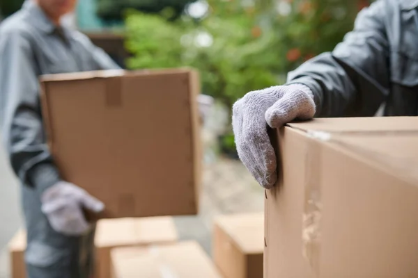 Closeup image of movers putting big cardboard boxes in van, delivery service concept