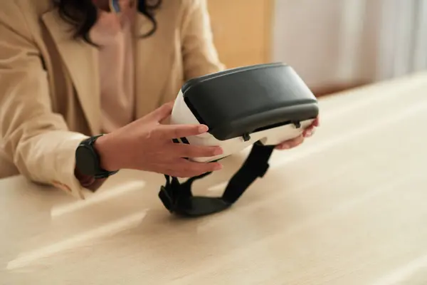 Close-up of young businesswoman using virtual reality glasses at her work while sitting at table