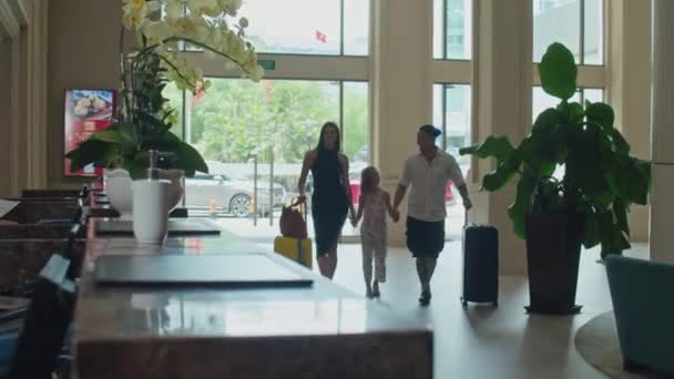 带着行李走向酒店大堂接待处办理入住手续的快乐家庭的全景 — 图库视频影像