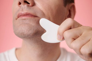 Gua sha aracı ile çene satırı masaj olgun adam yakın görüntü
