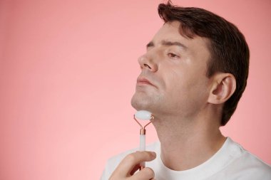 Orta yaşlı bir adam iki çeneden kurtulmak için yüz masajı yapıyor.