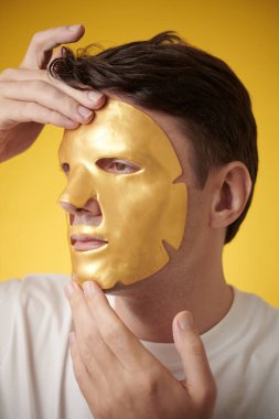 Tedavi sonrası deriyi yatıştırmak için hidrojel maskesi takan olgun bir adam.