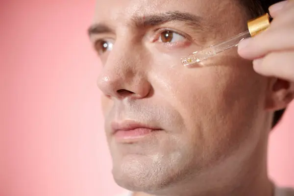 Mature man applying vitamin c serum on face to reduce wrinkles