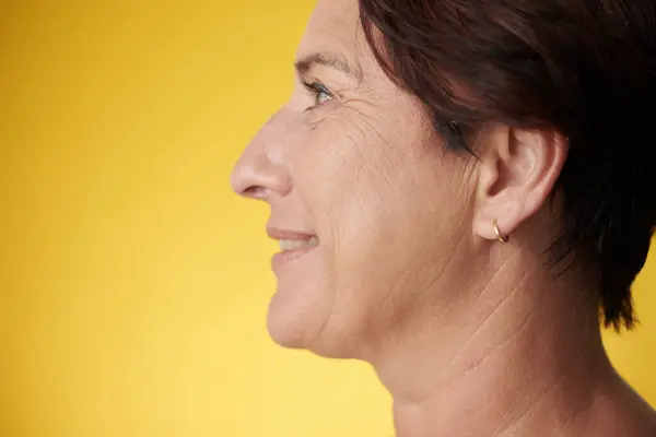 Profile of smiling mature woman with short hair, isolated on yellow