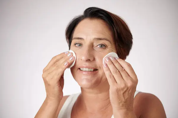 Portrait of mature woman applying toner on face