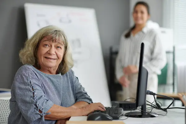 Portrait of smiling senior woman attending computer training class