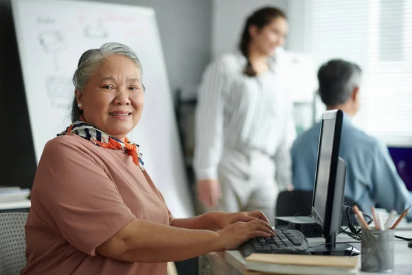 Portrait of smiling Vietnamese elderly woman attending computer class for seniors