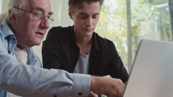 Średnie Ujęcie Dziadka Pokazującego Coś Swojemu Synowi Ekranie Bezprzewodowego Laptopa — Wideo stockowe