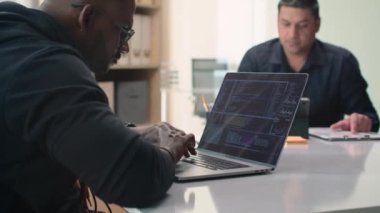 Dizüstü bilgisayarda çalışan programcıya odaklan. Kod ile ofiste erkek müdürle aynı masada oturuyor.