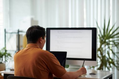 Yazılım geliştiricisi programlama kodunu gözden geçirir ve planlayıcıyla notlar alır