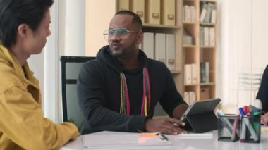 Erkek programcının iş arkadaşlarına ofisinde konferans yaparken dijital tablet üzerine yeni bir uygulama gösterirken orta boy görüntüsü.