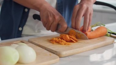 Kadın kasede salatayı karıştırırken, havuç kesen tanınmayan bir adamın ellerini kapatıyoruz. Yemek hazırlıyoruz.