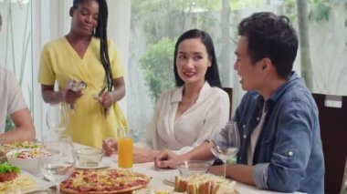 Orta boy Afrikalı Amerikalı genç bir kadının Asyalı çifte çatal bıçak getirdiği fotoğraf. Kutlama masasına hazırlanırken.