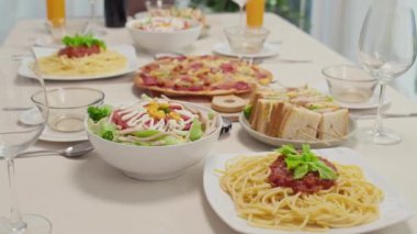 Pizza, makarna, sandviç, meyve suyu ve şarap bardaklarını kutlama masasına koyun.