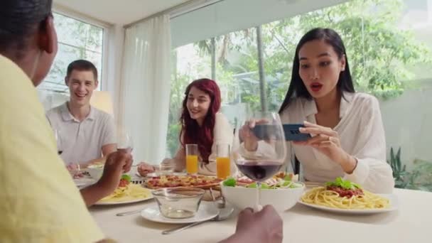 亚洲女人在和朋友在家里庆祝活动的同时 还用手机在节日桌上为不同的菜肴拍照 — 图库视频影像