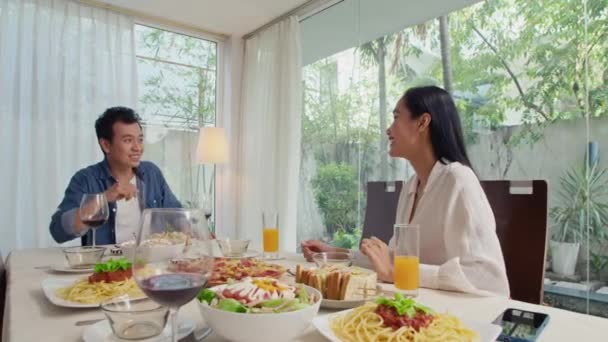 アジアのカップルは 自宅でお祝いのテーブルに座ってイベントを祝うために来る彼らの友人に挨拶 — ストック動画