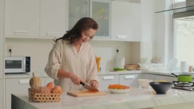 Mutfakta vitamin salatası pişirirken tahta tahtada havuç kesen orta boy bir kız resmi.