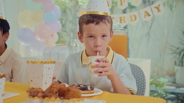 Portré Tinédzser Fiú Party Kalap Iszik Gyümölcslé Miközben Ünnepi Asztalnál — Stock videók