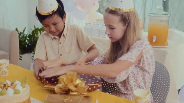 Medium Skud Multietnisk Dreng Pige Hatte Udpakning Fødselsdagsgave Mens Sidder – Stock-video