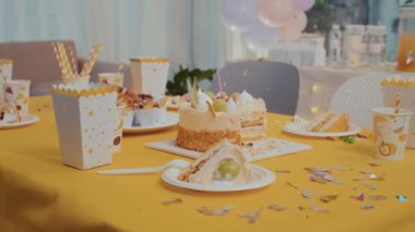 Doğum günü pastasıyla orta boy tabaklar, çocuklar için hazırlanmış patlamış mısır ve meşrubat kutuları.